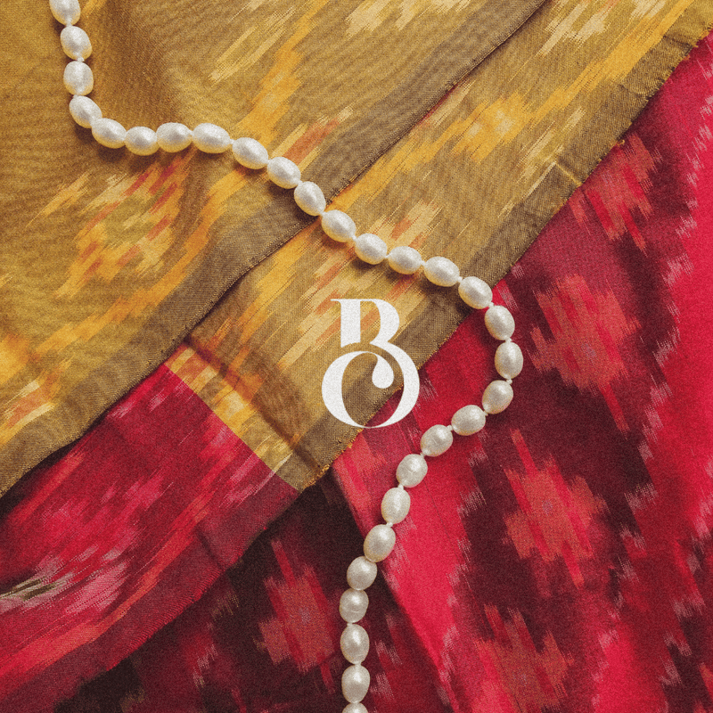 Strand of freshwater pearls on saree fabric with "B" logo